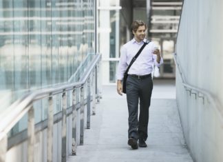 Sacs banane : comment la tendance traverse les générations A man carrying a computer bag with a strap across his chest on along a city walkway.
